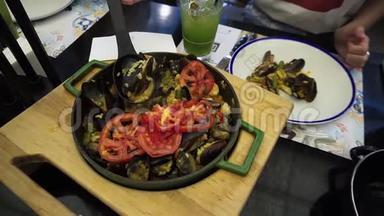 一个女孩在一盘传统的西班牙菜肴上倒入海鲜和蔬菜的海鲜饭。